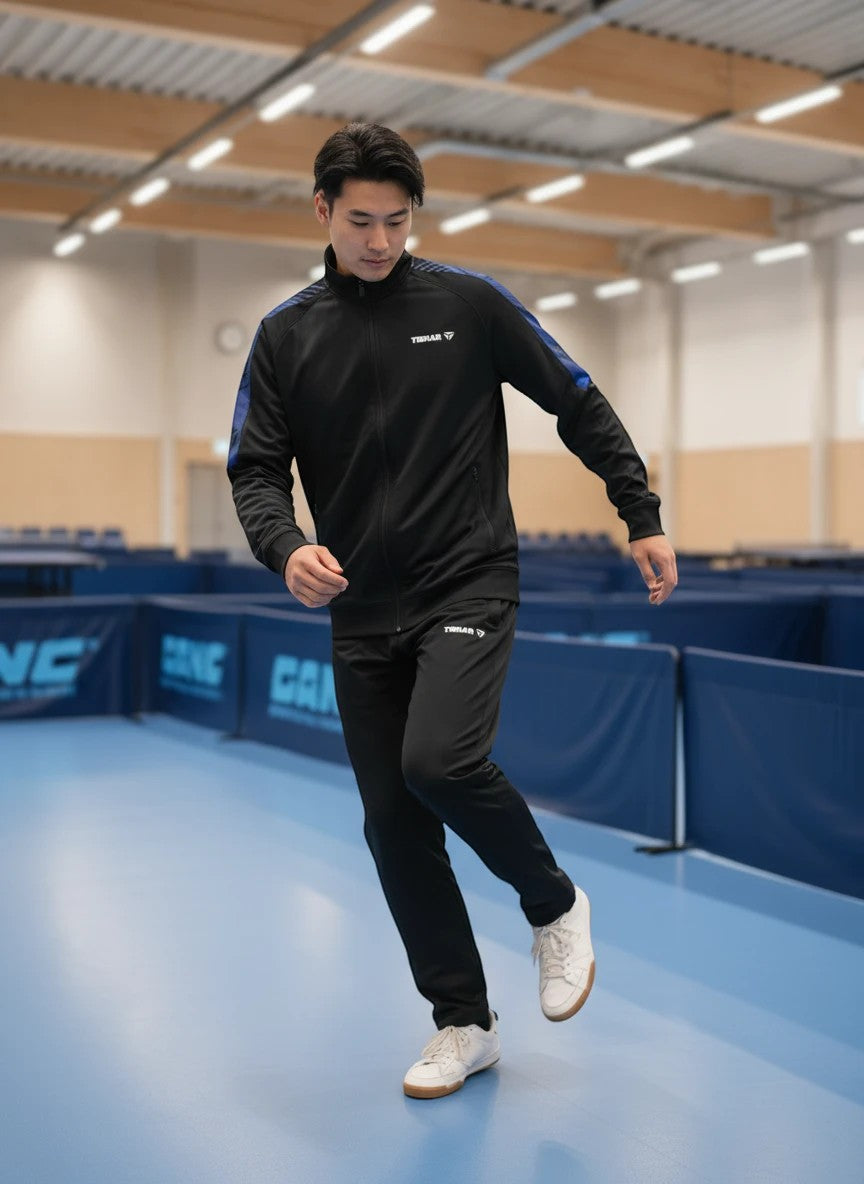 TTM-Store Tibhar DOMINO black polyester-elastane tracksuit with blue accents. Full zip jacket and pants for table tennis training.